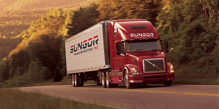 A red Volvo truck with a white trailer branded 'Sungor Transportation Inc' drives along a scenic, tree-lined highway at sunset.